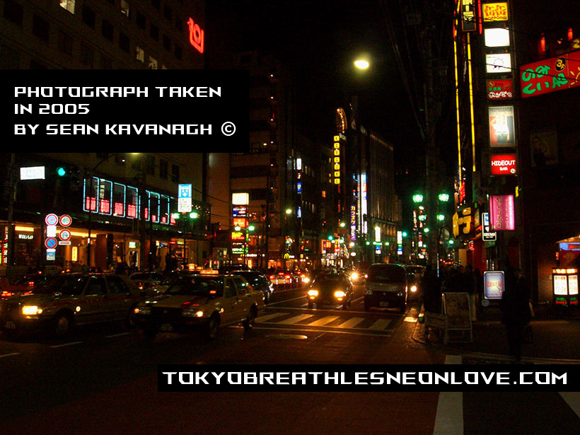 Taxis and cars move through the night amongst colored lights
  in Minato Ward - Tokyo.