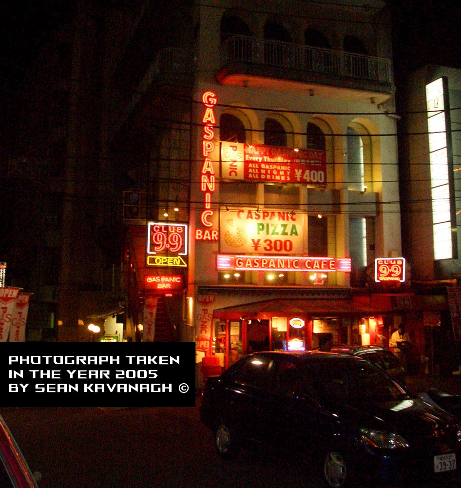 Bright, glowing signs adorn the entrance to the Gaspanic building in Roppongi. 
        Photograph by Sean Kavanagh.