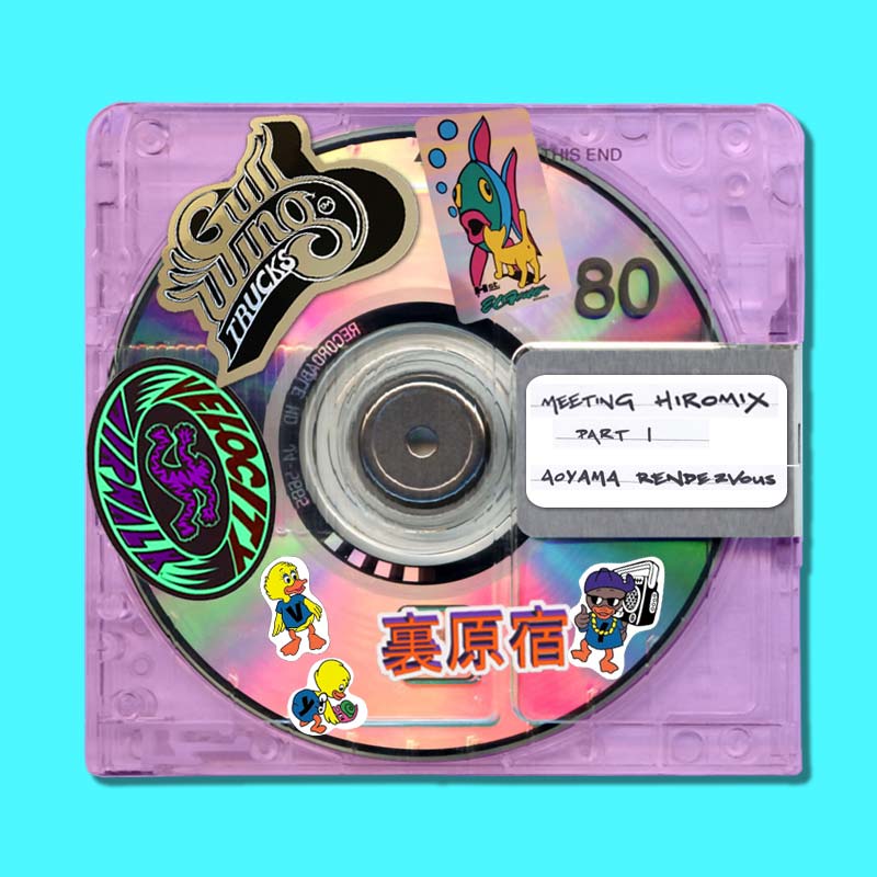 Image of a Purple MiniDisc with a white label with handwritten notes reading...
    'Meeting HIROMIX Part 1 - Aoyama Rendezvous'. The MiniDisc is covered with Skateboarding Stickers on the case.
     One sticker is a Gullwing Trucks sticker, another for Airwalk Velocity Shoes. There other stickers of little ducks, fish and a cat.