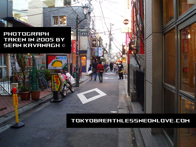 A photo I took from around a long time ago of a small side street in Harajuku with people wandering into
  the distance.